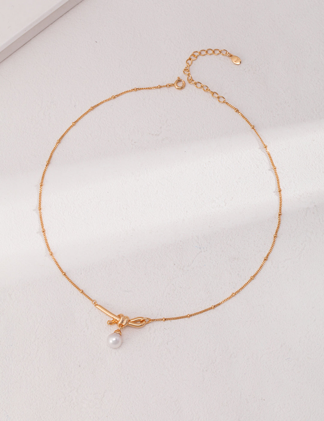 Knotted pearl necklace, shining like a star jewelry, with a delicate knot as a chain, a series of two white pearls, one large and one small, contrasting with each other.